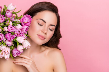 Photo of shiny charming woman naked shoulders holding flowers closed eyes empty space isolated pink color background