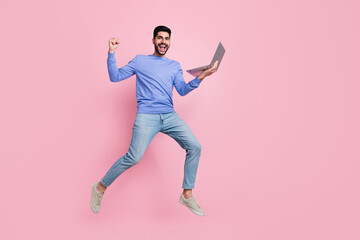 Fototapeta na wymiar Full length photo of pretty lucky guy dressed blue pullover jumping high communicating modern device isolated pink color background