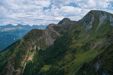 Fototapeta premium Alpine Meadows Trail, Krasnaya Polyana Resort. Alpine Meadows Walking Route. Aerial view of the green mountain valley, surrounded by high mountains.