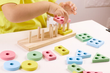 The child plays with colorful toy blocks. eco wooden toys. Little smart child playing natural toys. games for early development. Toy in children's hands close-up. selective focus