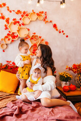 Mom and two little beautiful daughters in autumn with pumpkins and yellow leaves. Family cozy autumn day concept