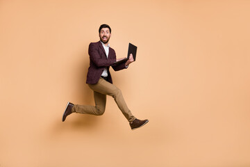 Full body image of overjoyed energetic businessman hurry to online meeting conference isolated on beige color background