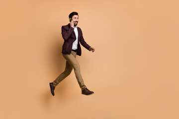 Fototapeta na wymiar Full length image of excited successful businessman go to work talk phone with colleagues isolated on beige color background