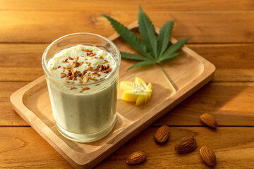 Selective focus of Bhang Lazzi Indian Tea with cannabis, almond crumbles, cannabis butter on wooden table in warm light background backdrop. Eatable recipe international coffee drinks herb concept