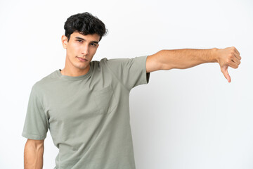Young Argentinian man isolated on white background showing thumb down with negative expression