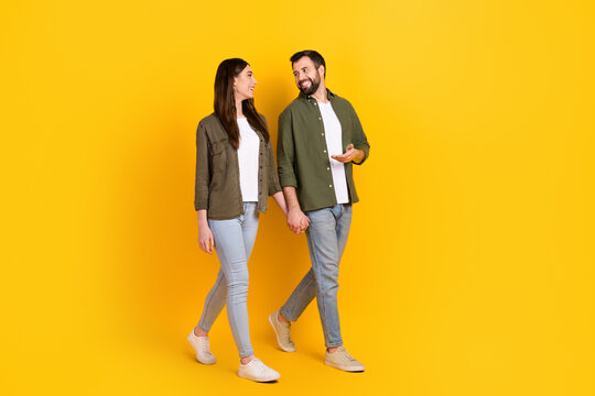Full length body size view of attractive cheerful couple spending day talking going isolated over bright yellow color background