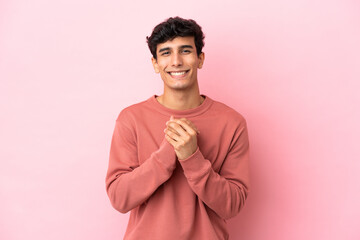 Young Argentinian man isolated on pink background laughing