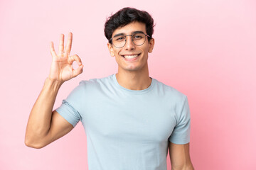 Obraz premium Young Argentinian man isolated on pink background With glasses and doing OK sign