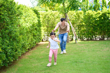 Naklejka na ściany i meble Girl running with her dad on home garden , Family playing time concept