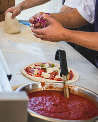 Italian pizza chef preparing and cooking pizza with mozzarella cheese tomato sauce and fresh basil leaf