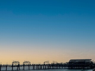 beautiful view of wooden bridge on the sea during the sunset in the autumn season.