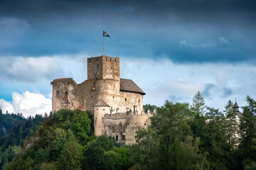 Fototapeta na wymiar Medieval castle in Niedzica, Poland. XIV century fortification located on top of the hill at the border of Pieniny National Park. Stronghold surrounded by trees. Flag waving over the castle.