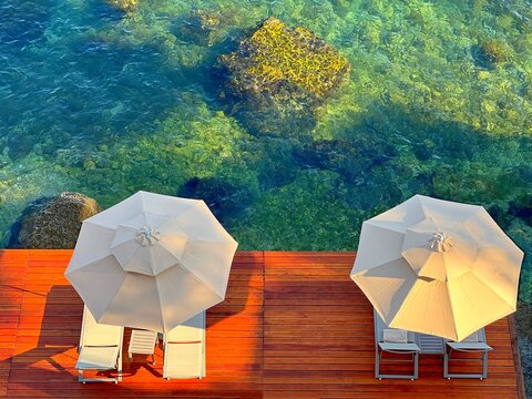 Beautiful beach and turquoise sea view. White umbrellas  and sunbeds on the secluded beach for happy relaxation.