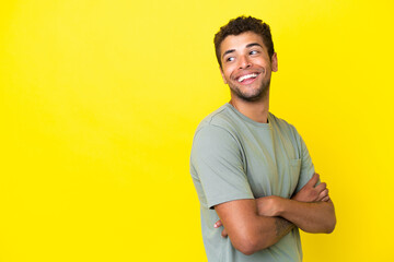 Young handsome Brazilian man isolated on yellow background happy and smiling