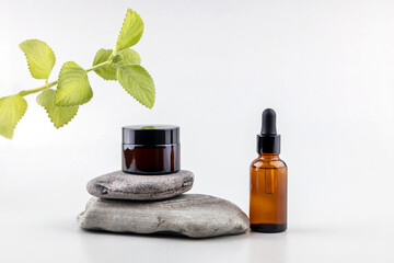 containers for cosmetics on the podium made of stone and a sprig of mint on a gray background