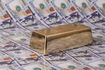 A large bar of gold and a bill of 100 American dollars