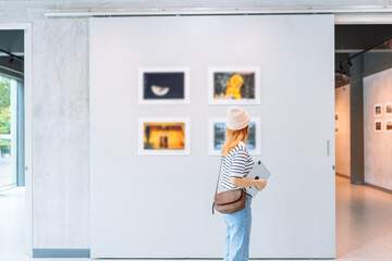 Woman visiting art gallery her looking pictures on wall watching photo frame painting at artwork museum people lifestyle concept.