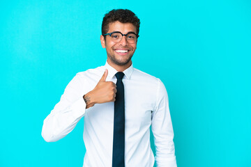 Young business Brazilian man isolated on blue background giving a thumbs up gesture