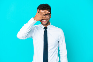 Young business Brazilian man isolated on blue background covering eyes by hands and smiling