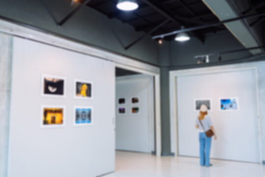 Blurred Woman visiting art gallery her looking pictures on wall watching photo frame painting at artwork museum people lifestyle concept.