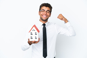 Young business Brazilian man holding a house toy isolated on white background doing strong gesture
