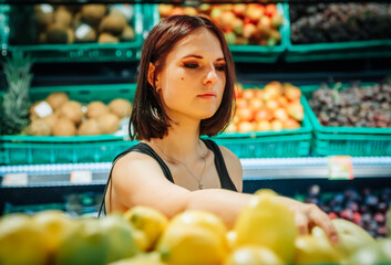 young woman in supermarket choosing grapefruits