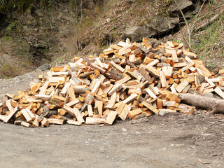 A pile of chopped firewood on the ground. Firewood piled under the hill