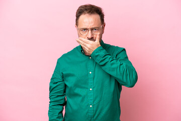 Middle age caucasian man isolated on pink background covering mouth with hand