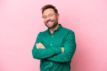 Middle age caucasian man isolated on pink background with arms crossed and looking forward