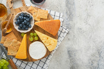 Assortment of cheese, honey, cracker, blueberries, grapes with red and white wine in glasses...