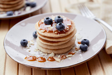 Pancakes with fresh blueberries and agave syrup on a plate close up. Healthy vegan food. Breakfast outside