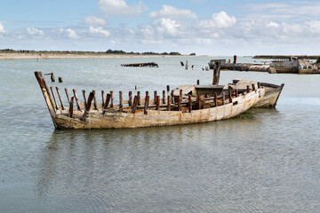 Cimetière de bateaux en bois dans un étier à marée haute derrière une jetée. Port de...