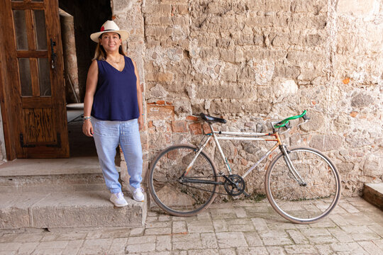 Latina morena parada en la puerta junto a una bicicleta