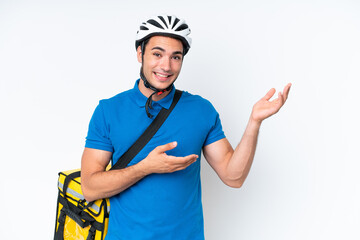 Young caucasian man with thermal backpack isolated on white background extending hands to the side for inviting to come