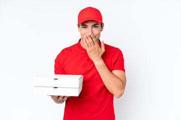 Pizza delivery caucasian man with work uniform picking up pizza boxes isolated on white background happy and smiling covering mouth with hand