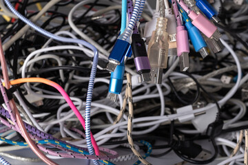 Pile of tangled old smart technology wires, used charging cables and connectors for electronic...