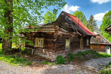 Fototapeta na wymiar Damaged old wooden cottage with destroyed roof