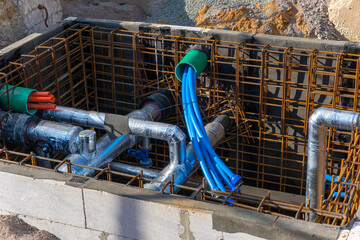 Water main pipe system on construction site. New communication in street city in the ground, surrounded by concrete and iron bars. Laying underground water system for residential buildings.