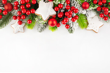 Branches of a Christmas tree with red and white decor on a white background with space for writing text.