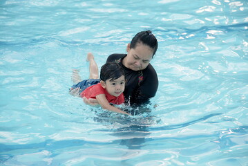 Mother teaching her son to swim in swimming pool