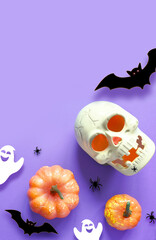Halloween decorations on purple background. Happy Halloween concept. Flat lay pumpkins, scull, bats, ghost and spiders.