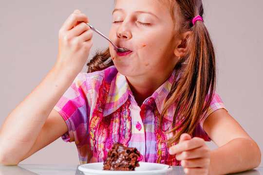 Portrait of cute attractive amazed young girl eating a chocolate cake