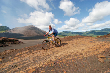 Fototapeta na wymiar Western tourist riding a mountain bike on Yasur Volcano, Tanna Island, Vanuatu