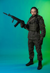 soldier in the studio on a green background with colored light. a man in military uniform with a gun, rifle or machine gun. military. airball player