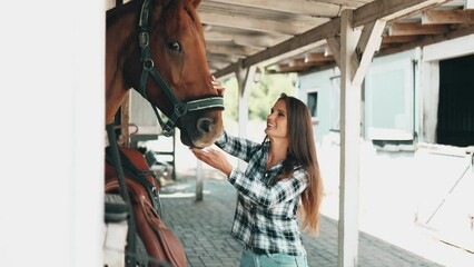 Woman taking care of her horse in stable

