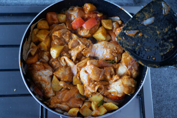 cooking chicken curry in a cooking pan 