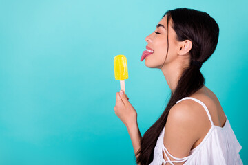 Profile side photo of cute pretty lady lick frozen tasty fruit popsicle isolated aquamarine color background - obrazy, fototapety, plakaty
