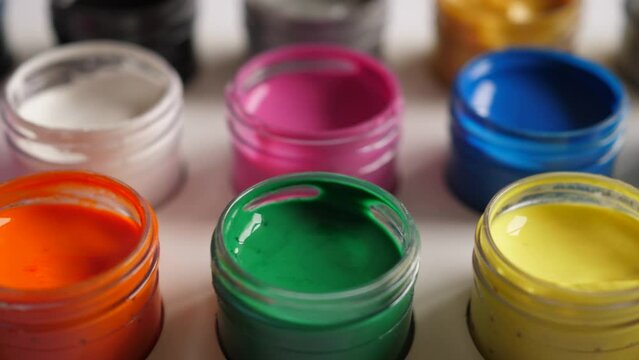 Set Gouache Paints in Jars Bright Color Close Up. Set of Multicolor Gouache on Plastic Jars. Dolly Shot Multicolor Background. Background of Multi Colored Paint. Creative Drawing Art Hobby.