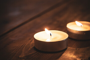 two burning candles on top of a brown wooden table