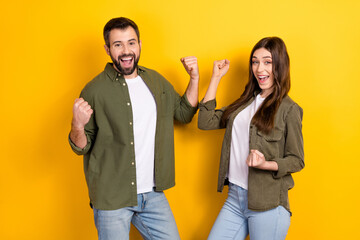 Photo of two delighted overjoyed people raise fists celebrate luck isolated on yellow color background